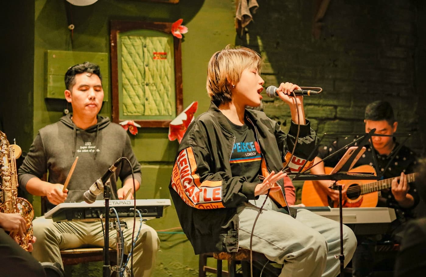 Grupo tocando junto em um espaço pequeno, com público próximo